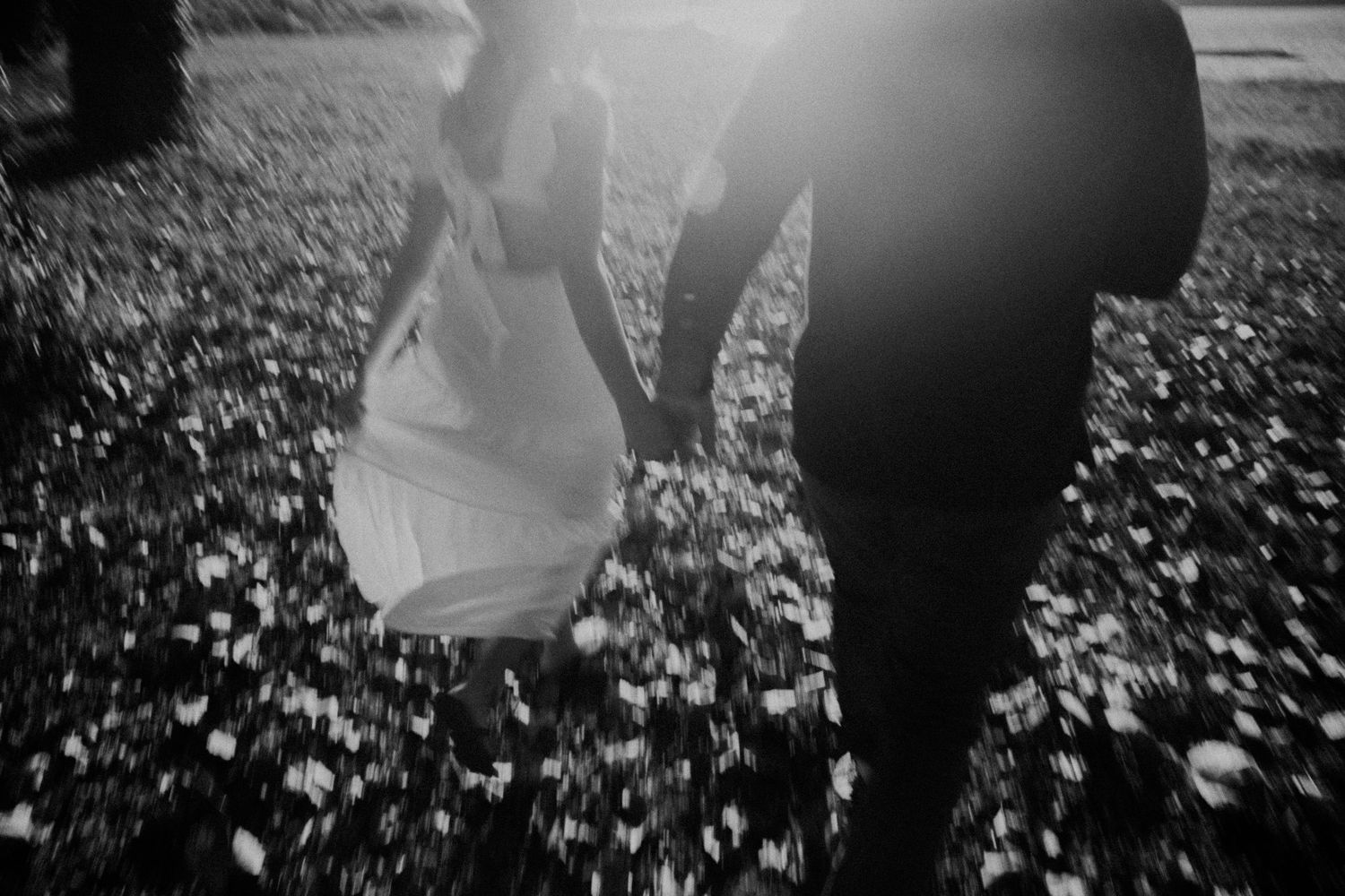 Silhouettes of a couple walking through a sunlit field with scattered leaves.