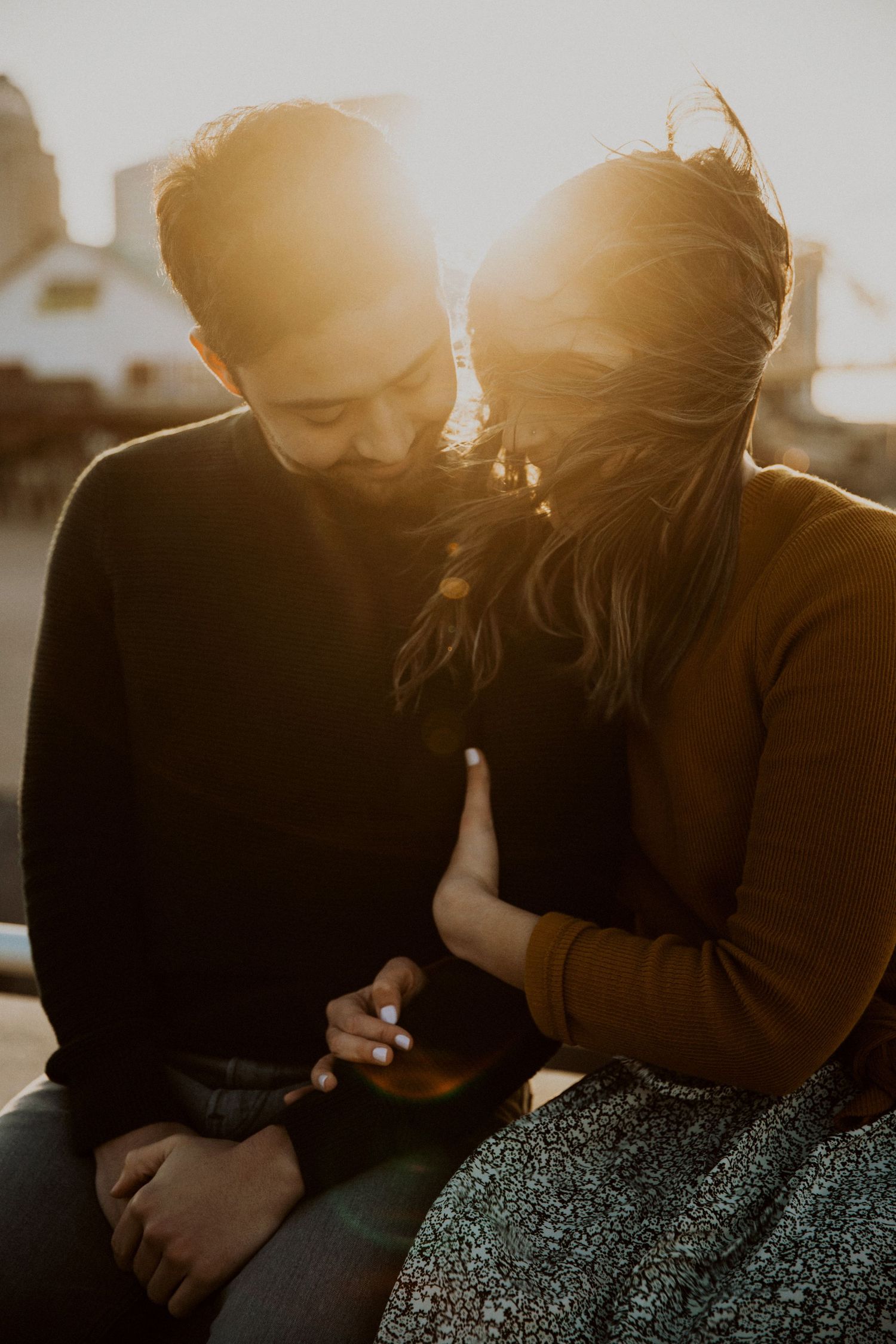 A couple shares an intimate moment silhouetted against a warm sunset glow.