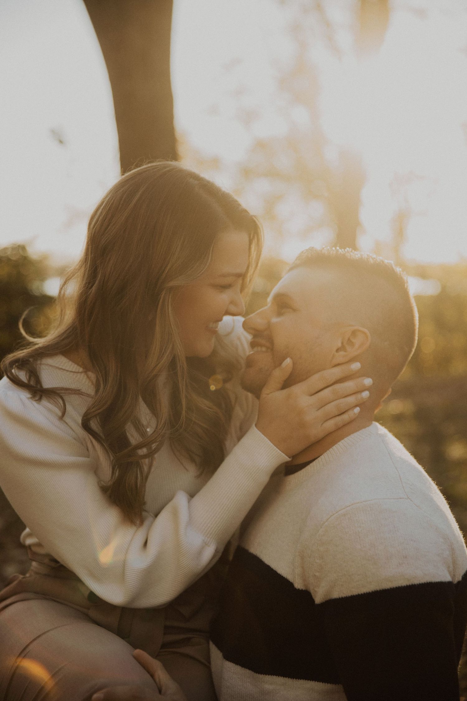 A couple sharing romantic moments during golden hour in a forest setting.