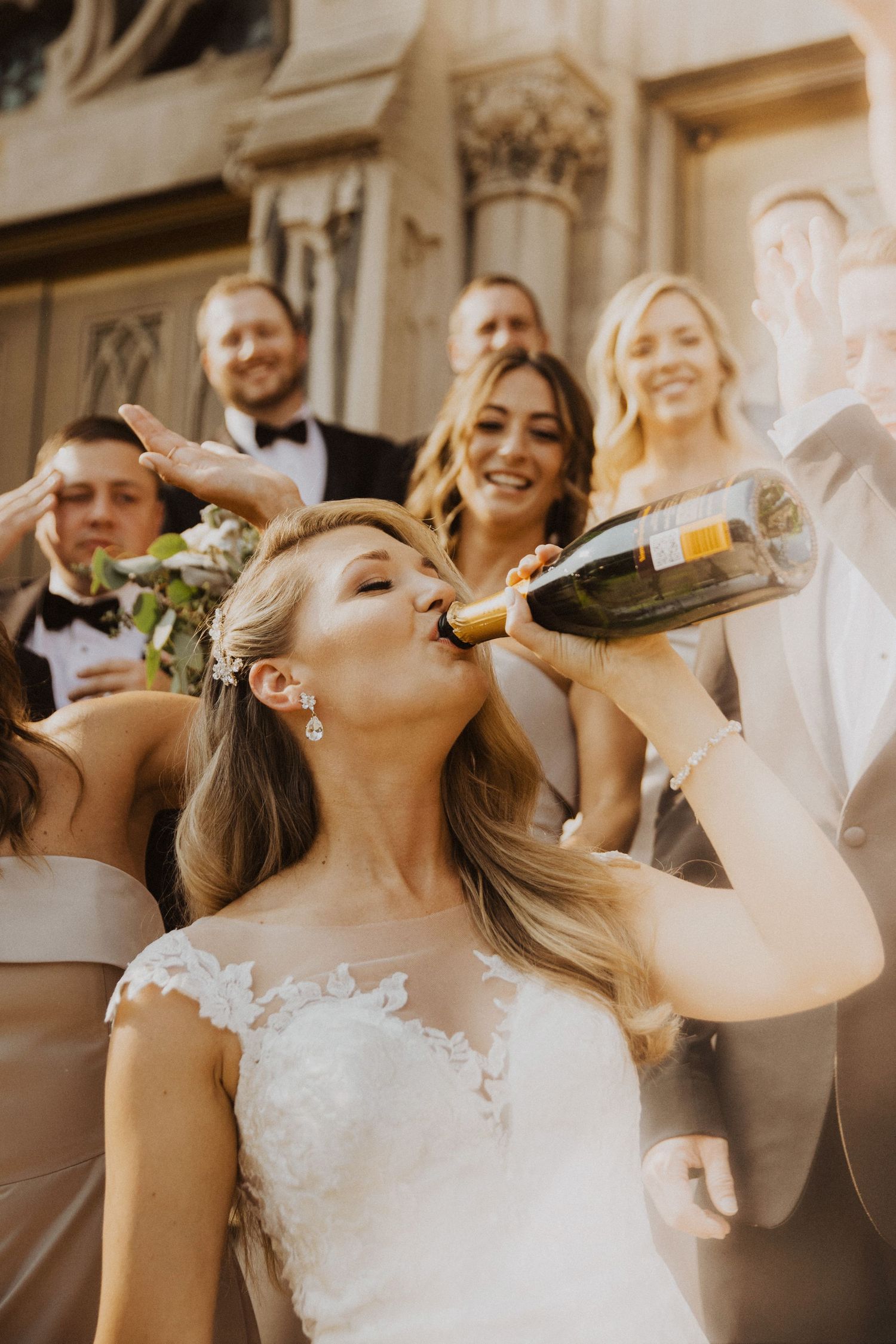 Wedding party celebrates with champagne bottles in a fun candid moment.