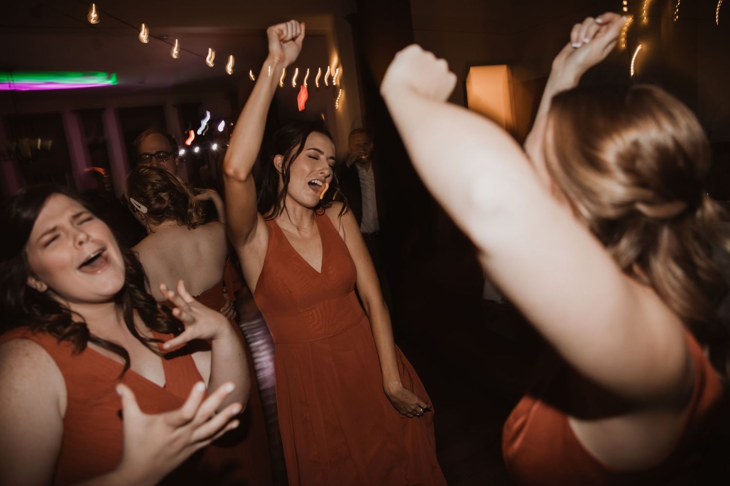 Energetic dance party scene with guests celebrating at a wedding reception.