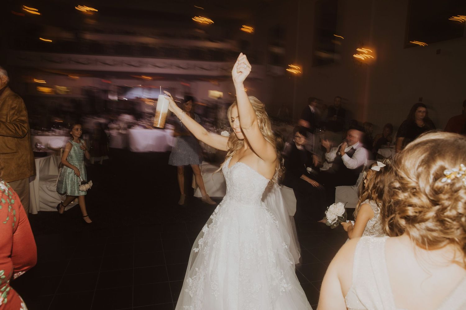 Wedding celebration with dancing guests under warm lighting.