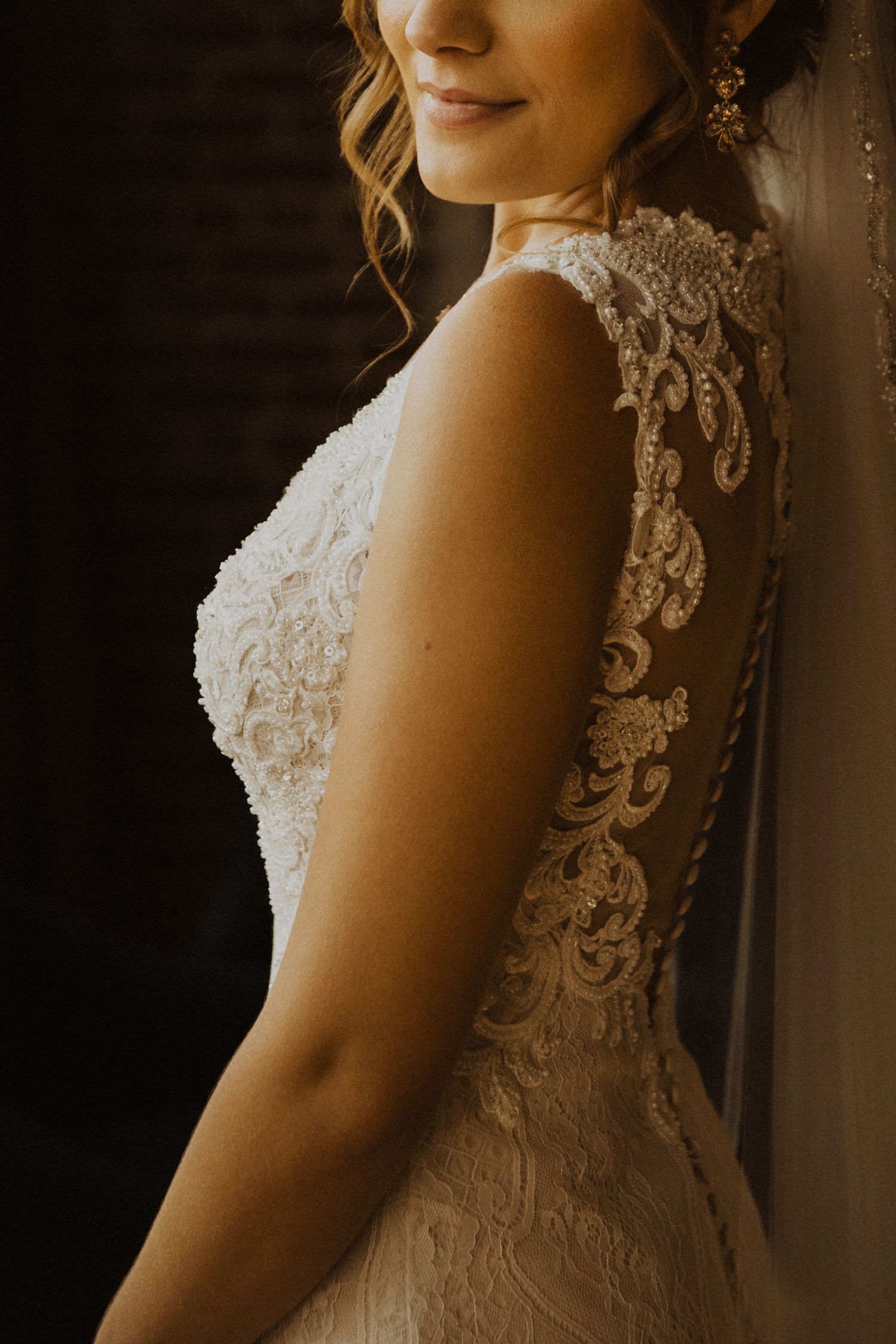 Close up details of intricate lace patterns on back of wedding gown in natural window light.