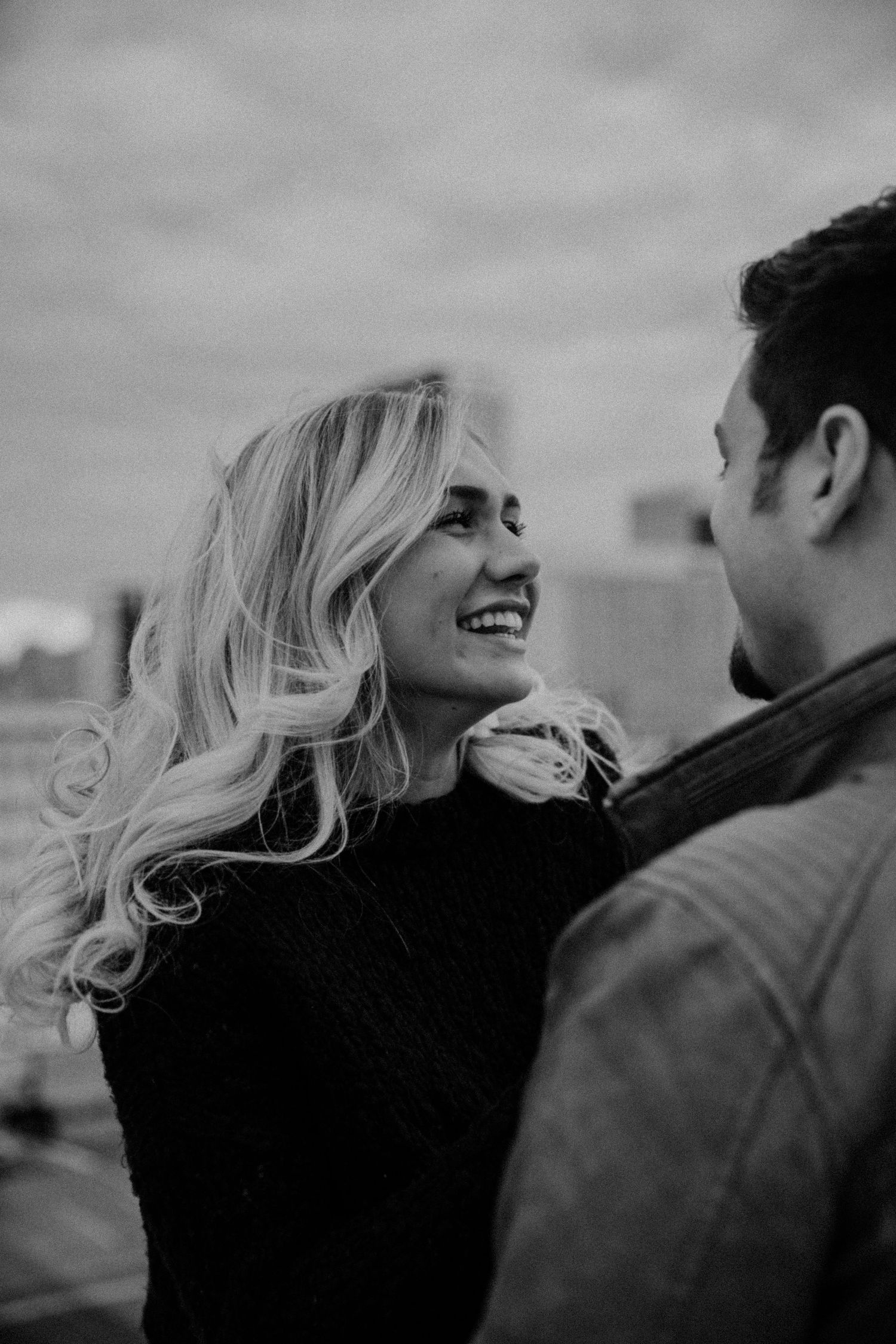 A romantic black and white photo series showing a couple laughing together outdoors.