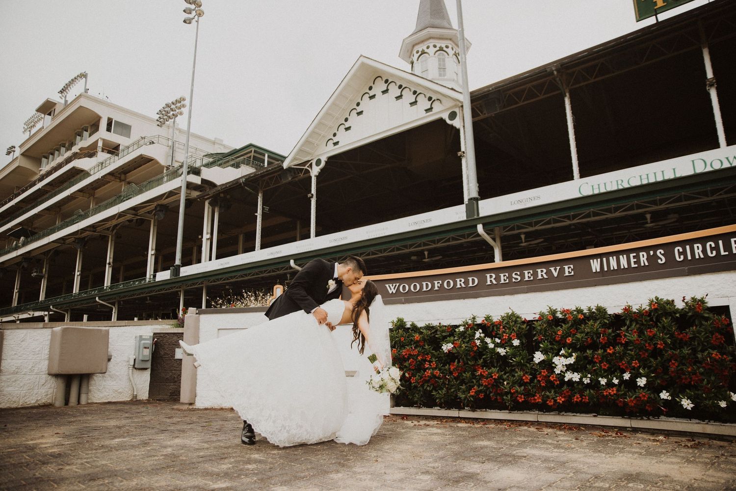 Wedding photos taken at a racetrack with classic architecture in the background.