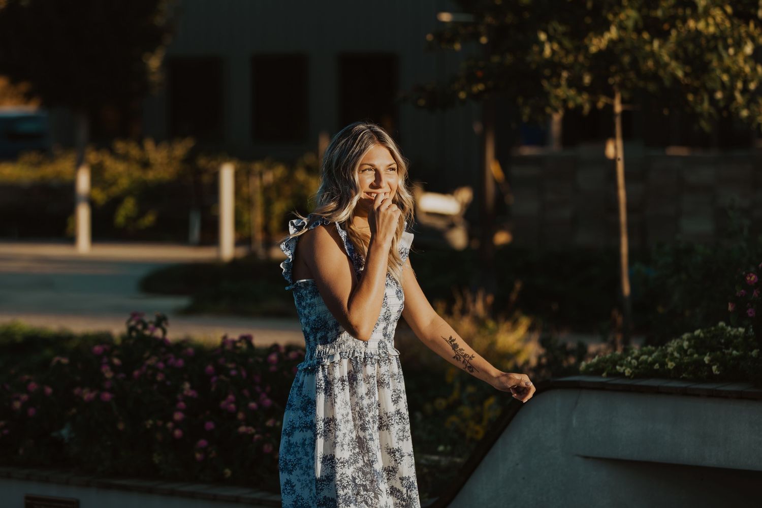 Woman in floral dress showing excitement and surprise in an outdoor setting at sunset.