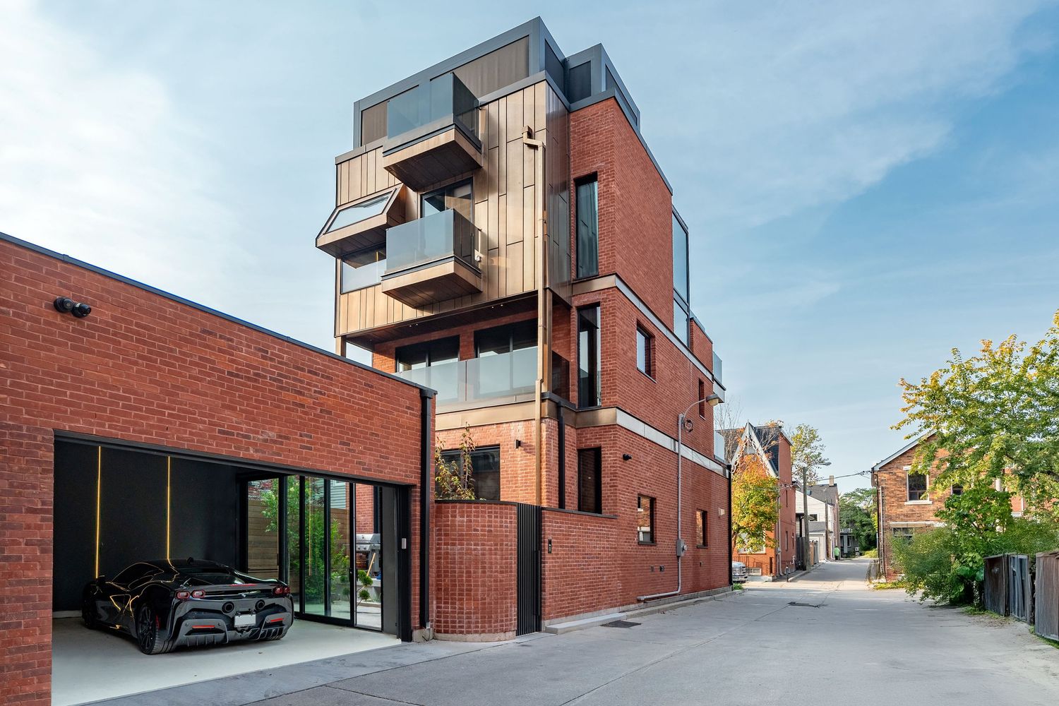 Modern multi-story red brick building with cantilevered wood balconies and open garage featuring a black sports car.