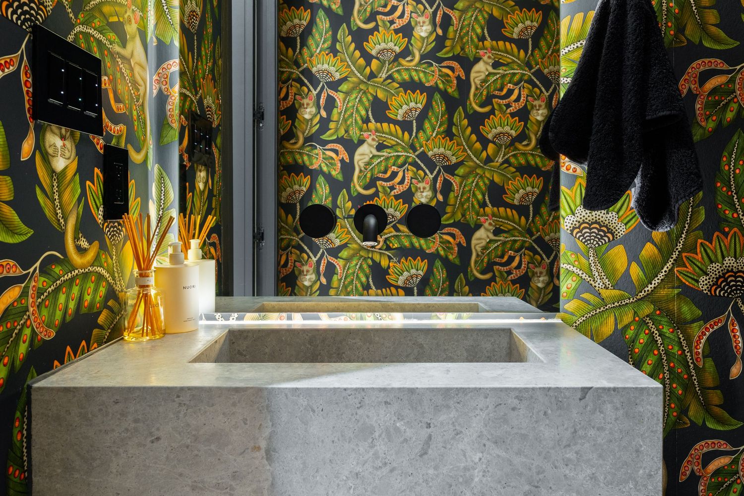 Luxurious bathroom featuring bold tropical floral wallpaper and a sleek marble sink with modern fixtures.