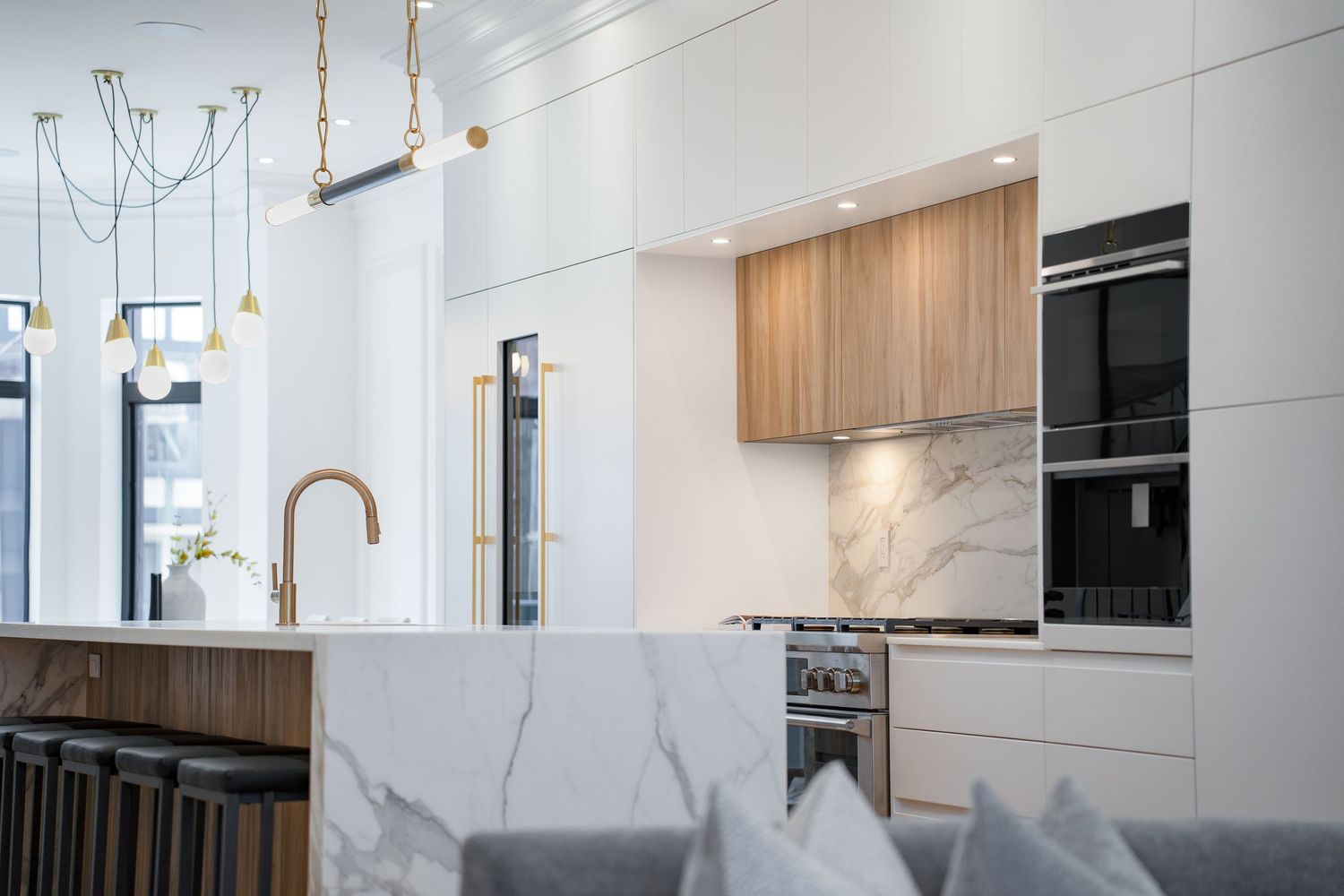 Elegant white kitchen featuring marble backsplash, warm wood cabinets, brass fixtures, and luxury pendant lighting. 22 Shannon St, Toronto.