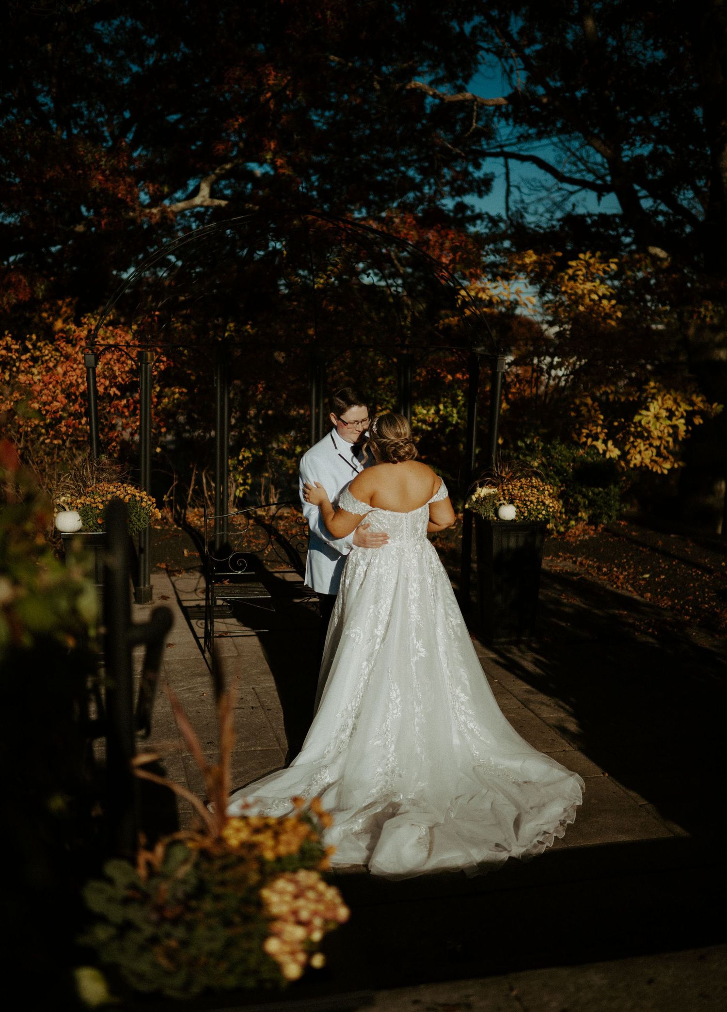 Newlyweds sharing vows surrounded by vibrant autumn foliage in outdoor garden setting.