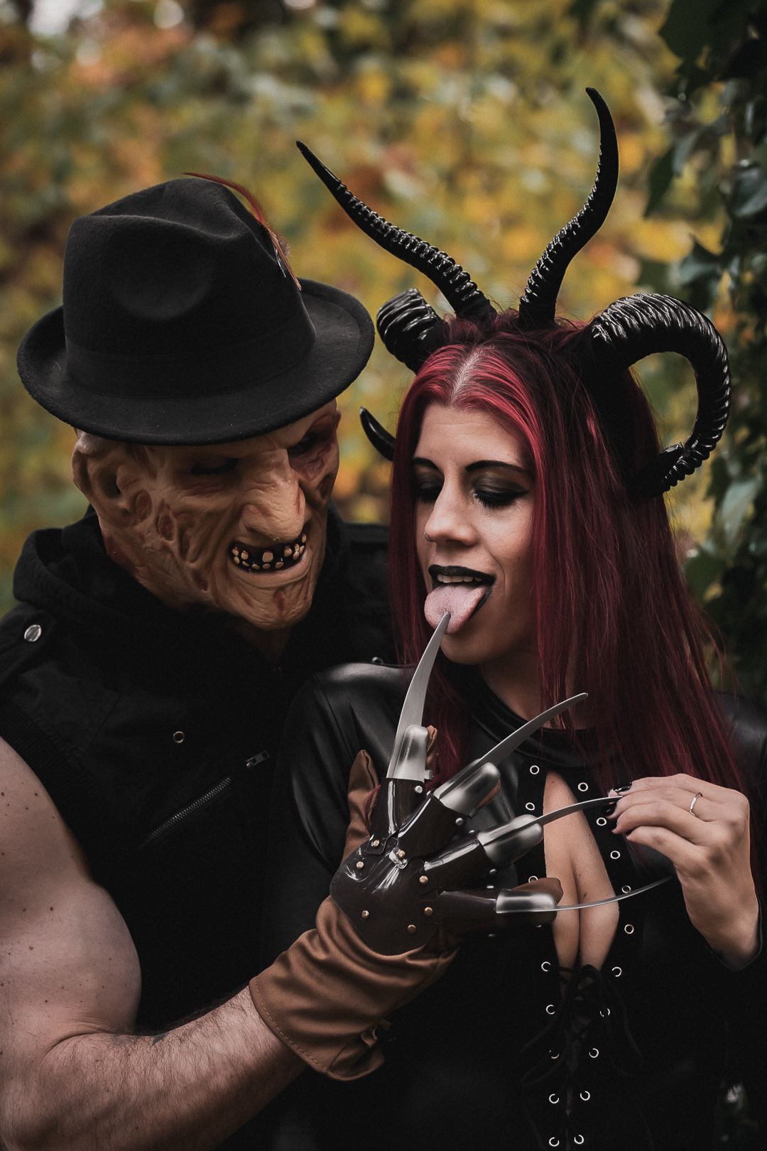 Couple in Halloween costumes as Freddy Krueger and a devil with horns outdoors.