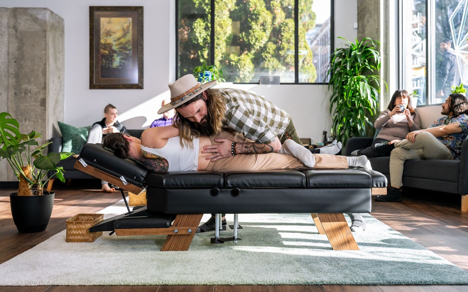 Chiropractor performing spinal adjustment on patient lying on treatment table in modern wellness studio.