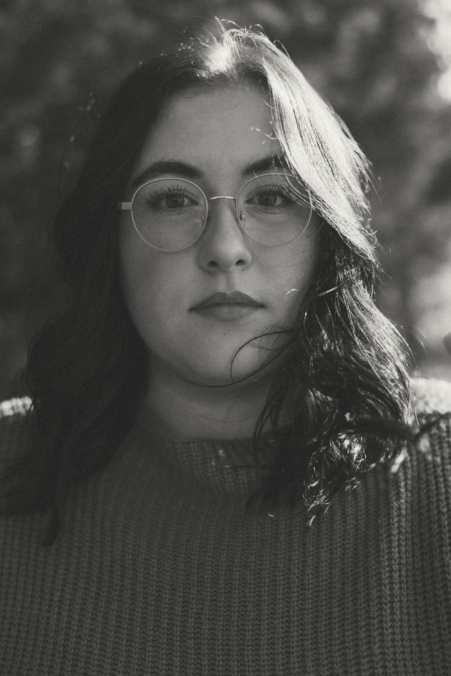 Black and white portrait showing a person wearing glasses and a knit sweater.