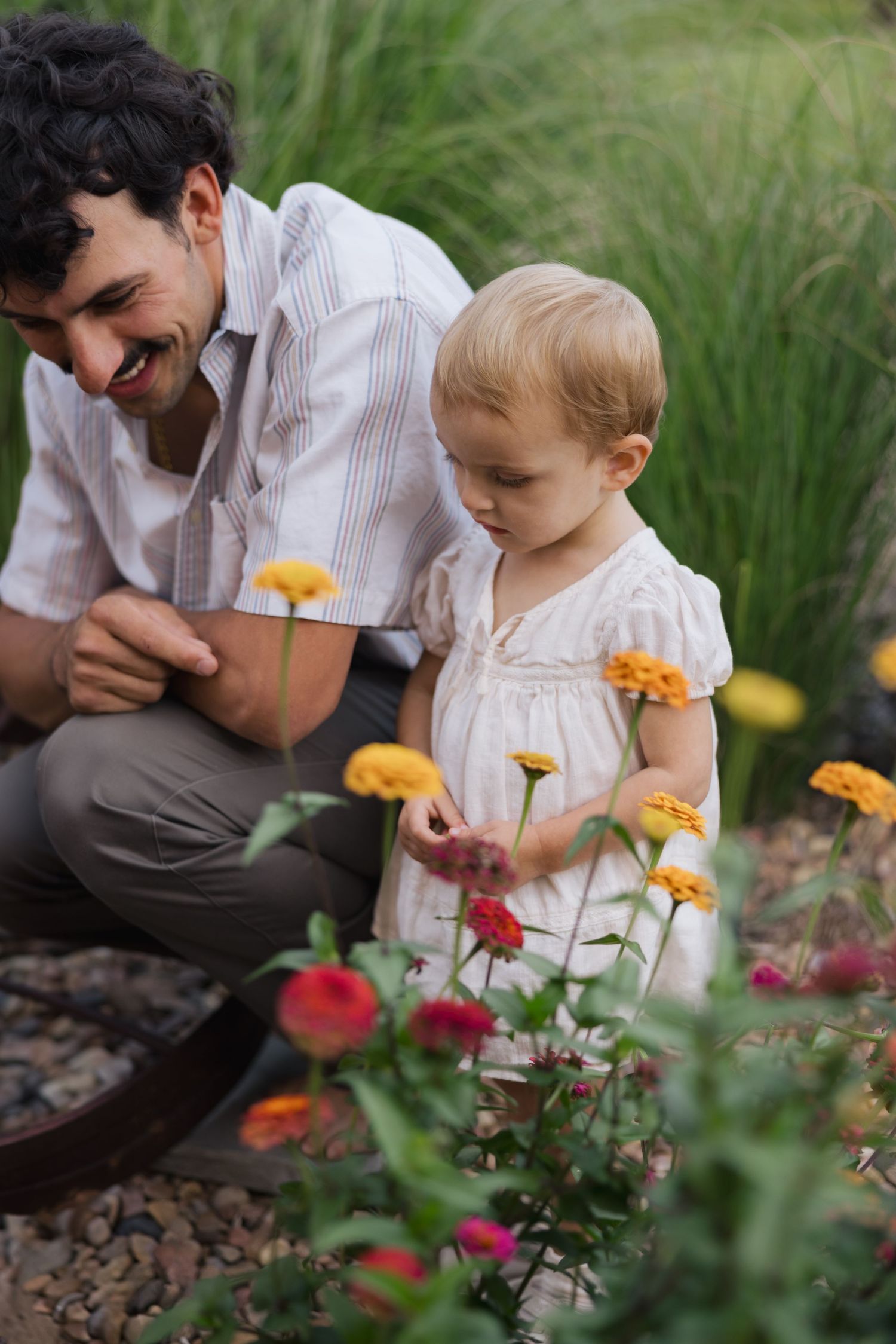 Adult and child looking at colorful flowers in garden together.