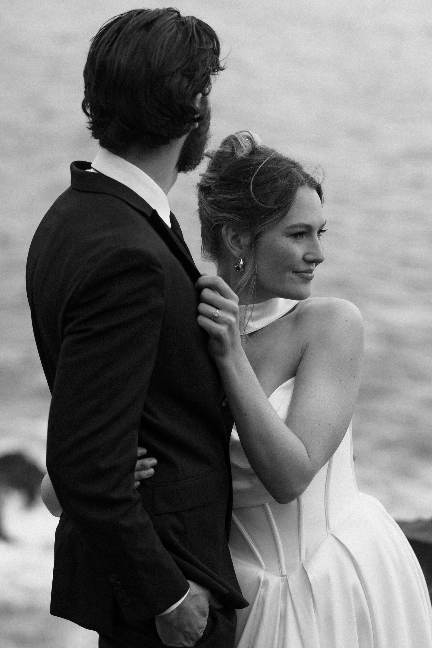 Black and white photo of couple embracing by the ocean.