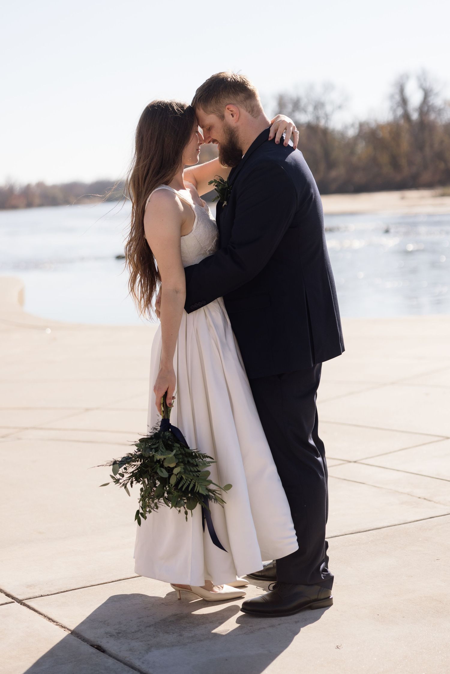 Romantic couple in formal wear sharing an intimate moment by the waterfront.