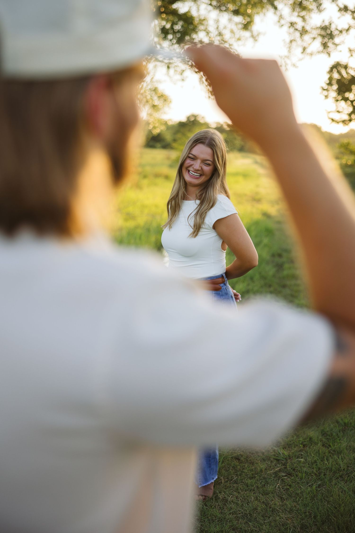 A couple shares playful moments in a sun-drenched field at sunset.