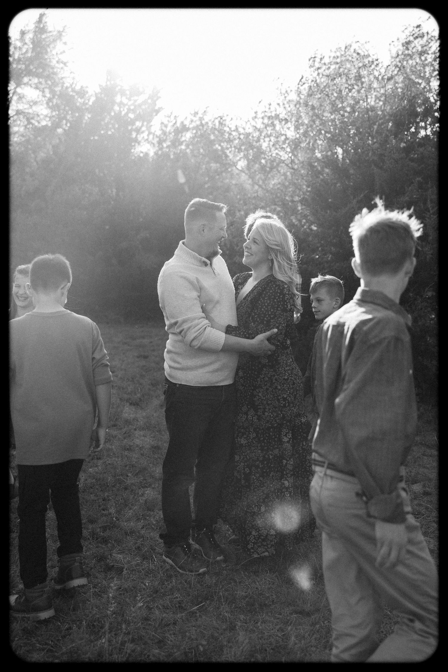 Black and white photo of people dancing together in an outdoor setting at dusk.