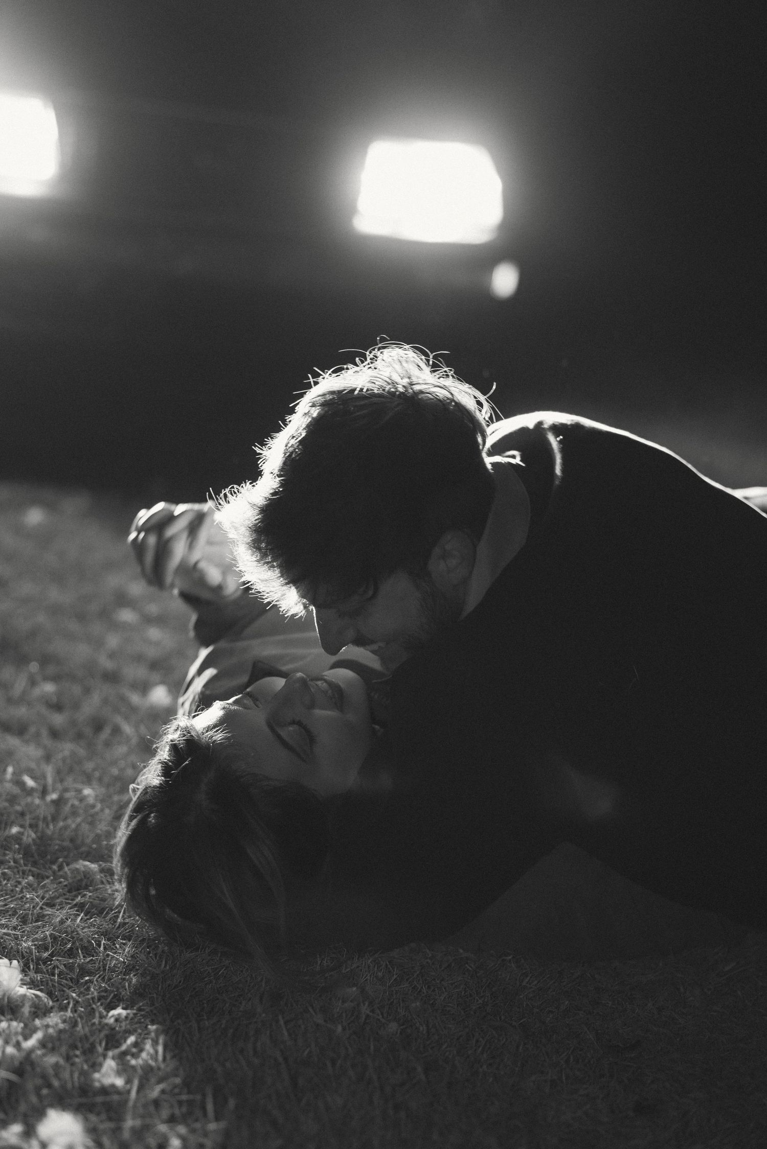 Intimate black and white nighttime portrait illuminated by dramatic lighting.