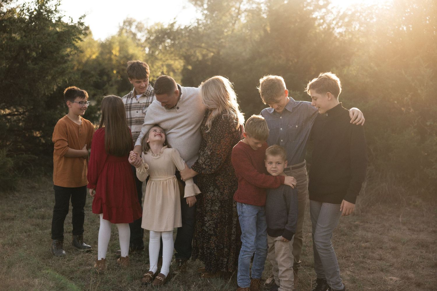Family gathering outdoors during golden hour with sunlight streaming through trees.