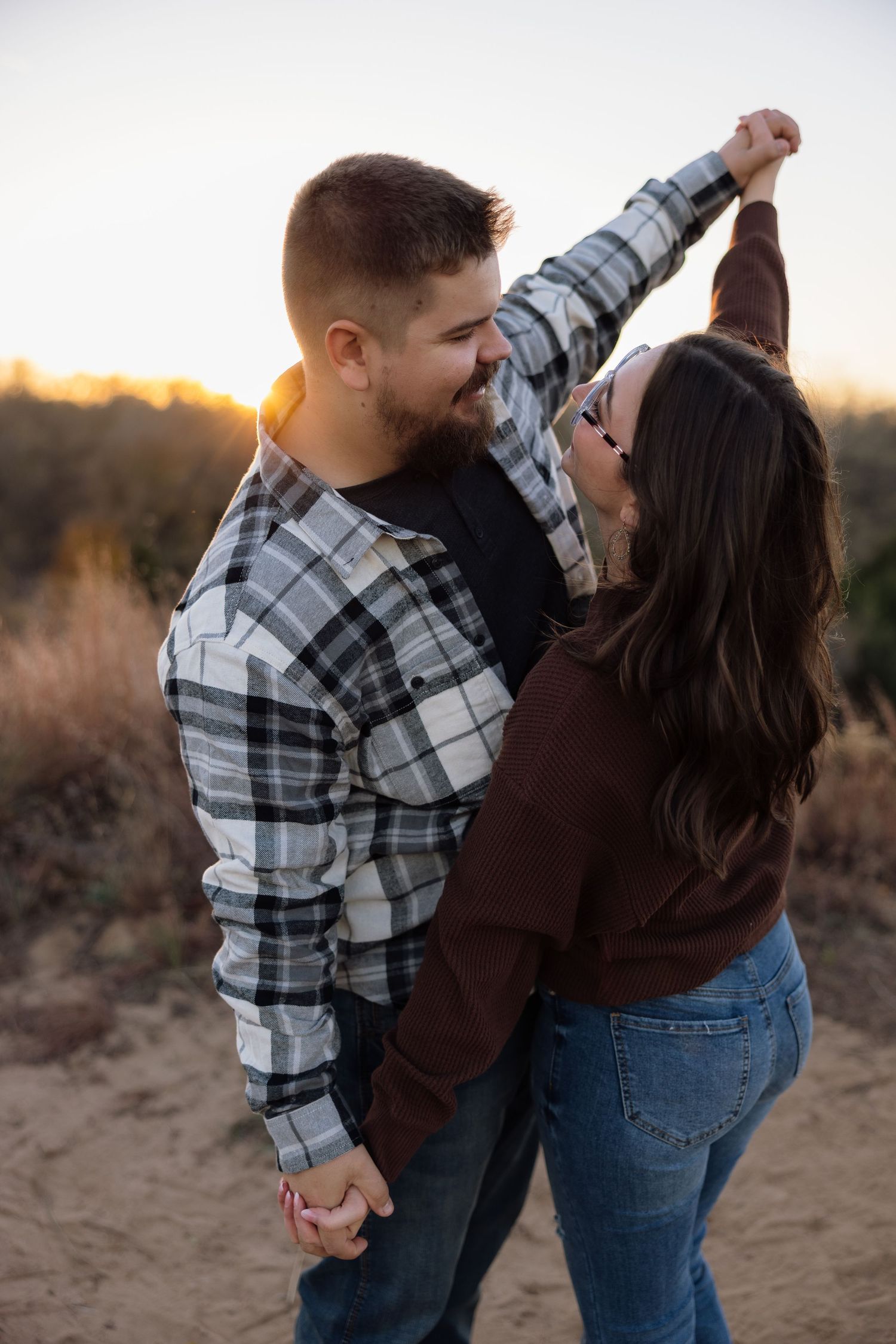 Couple dancing together on sandy terrain at sunset.