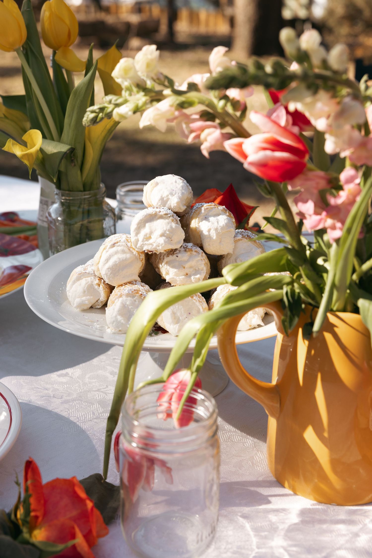 Wedding reception table decorated with colorful flowers in mason jars and yellow vases.