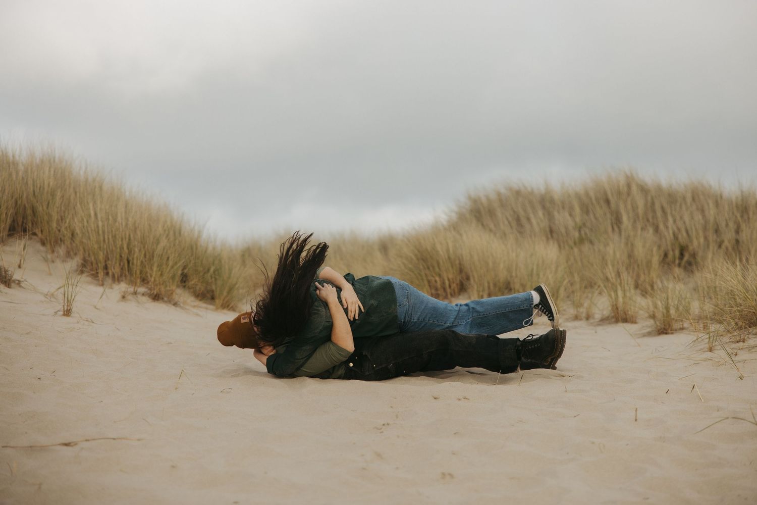People lying down on sandy dunes during an outdoor photoshoot.