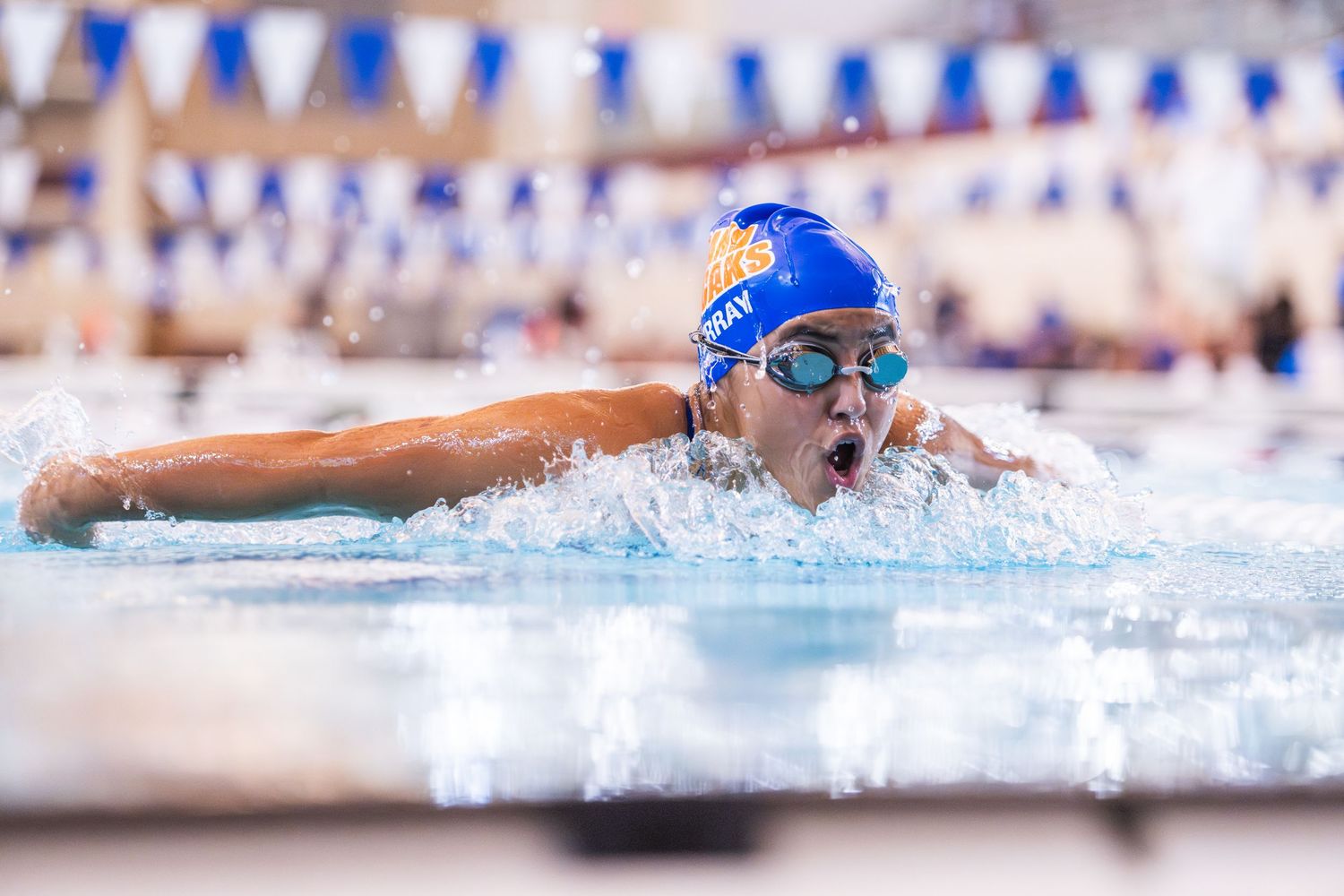 A competitive swimmer performs the butterfly stroke during a swim meet.