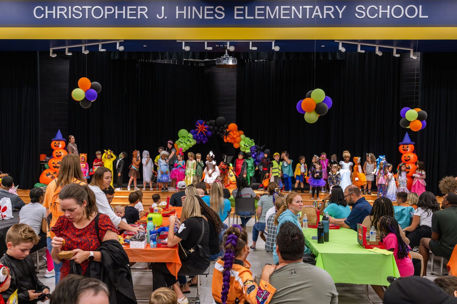 Students and families celebrate a festive Halloween event in the gymnasium at Christopher J. Hines Elementary School.