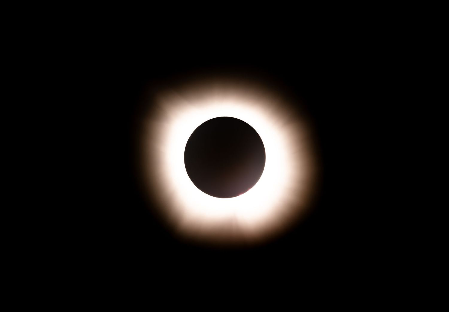 Stunning total solar eclipse with glowing white corona visible against a dark black sky.