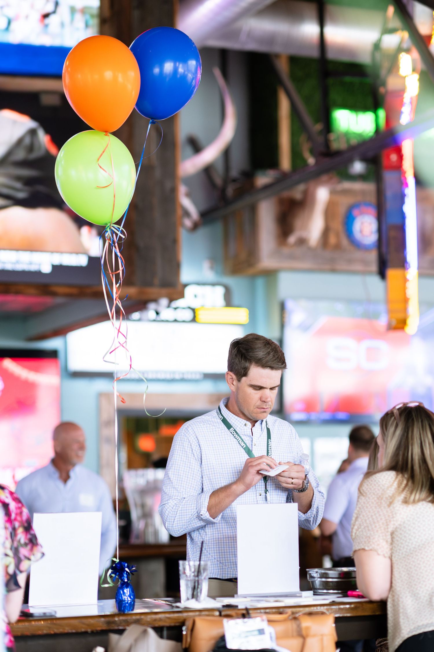 Young man checking registration materials at a colorful event welcome table with balloons.