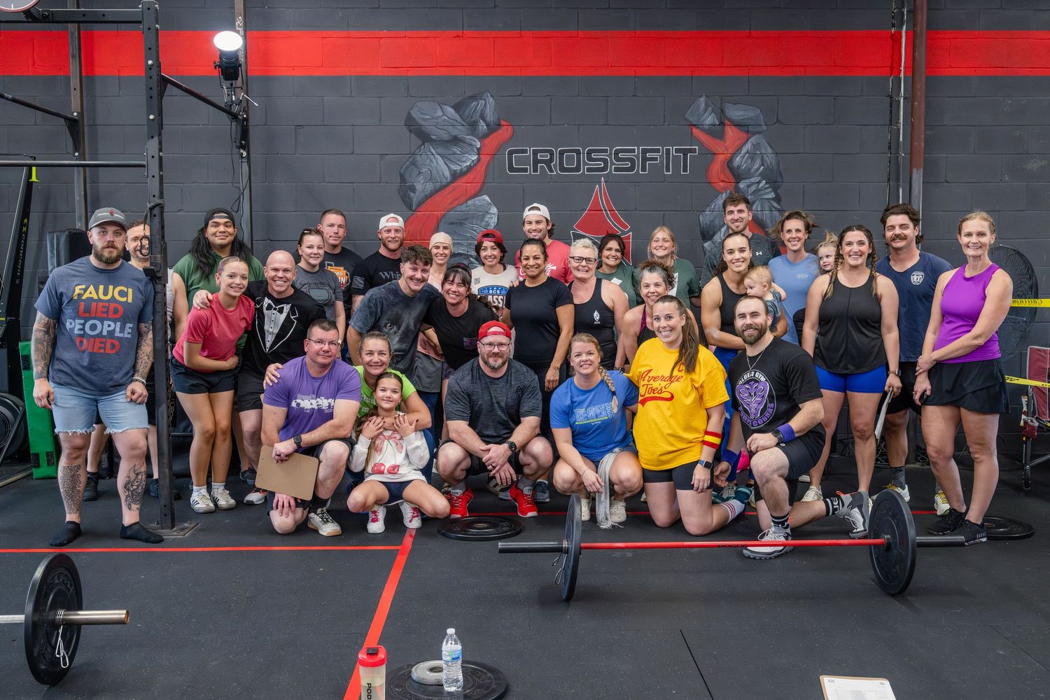 Large group of CrossFit athletes posing together in front of a CrossFit gym logo.