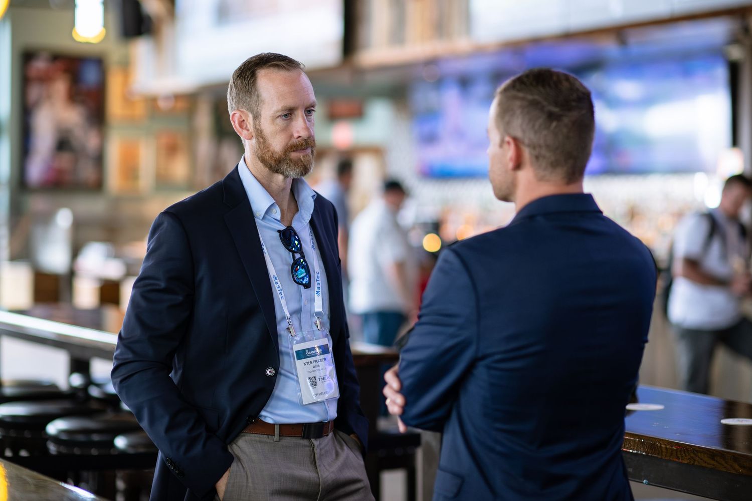 Two businessmen in suits having a conversation at a professional networking event.