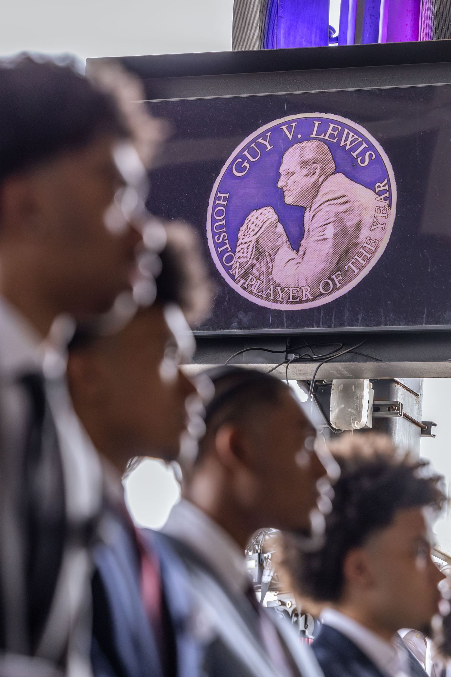 Men in suits stand before a screen displaying the Guy V. Lewis Houston Player of the Year award medallion.