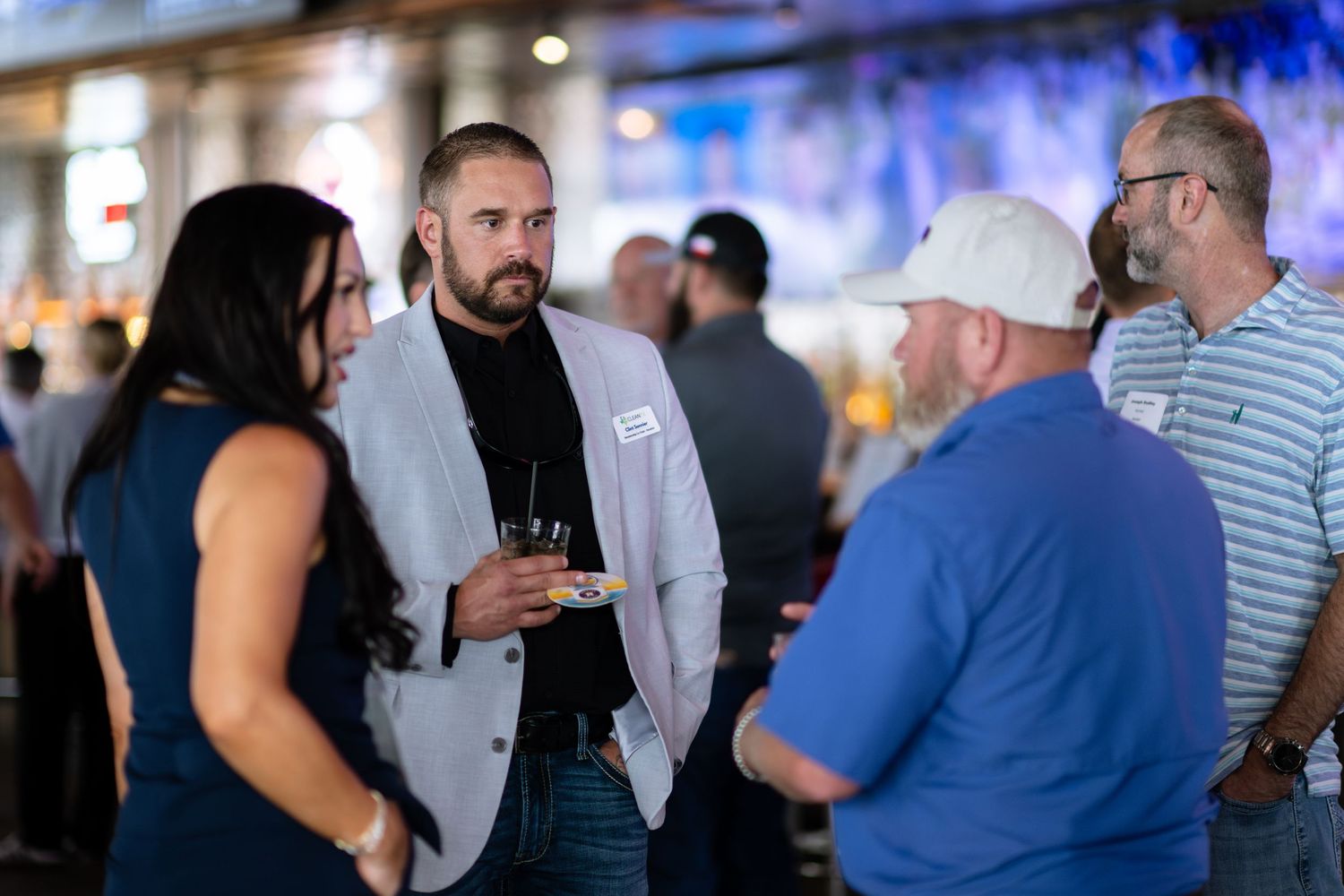 Three professionals networking and conversing at an evening social event outdoors.