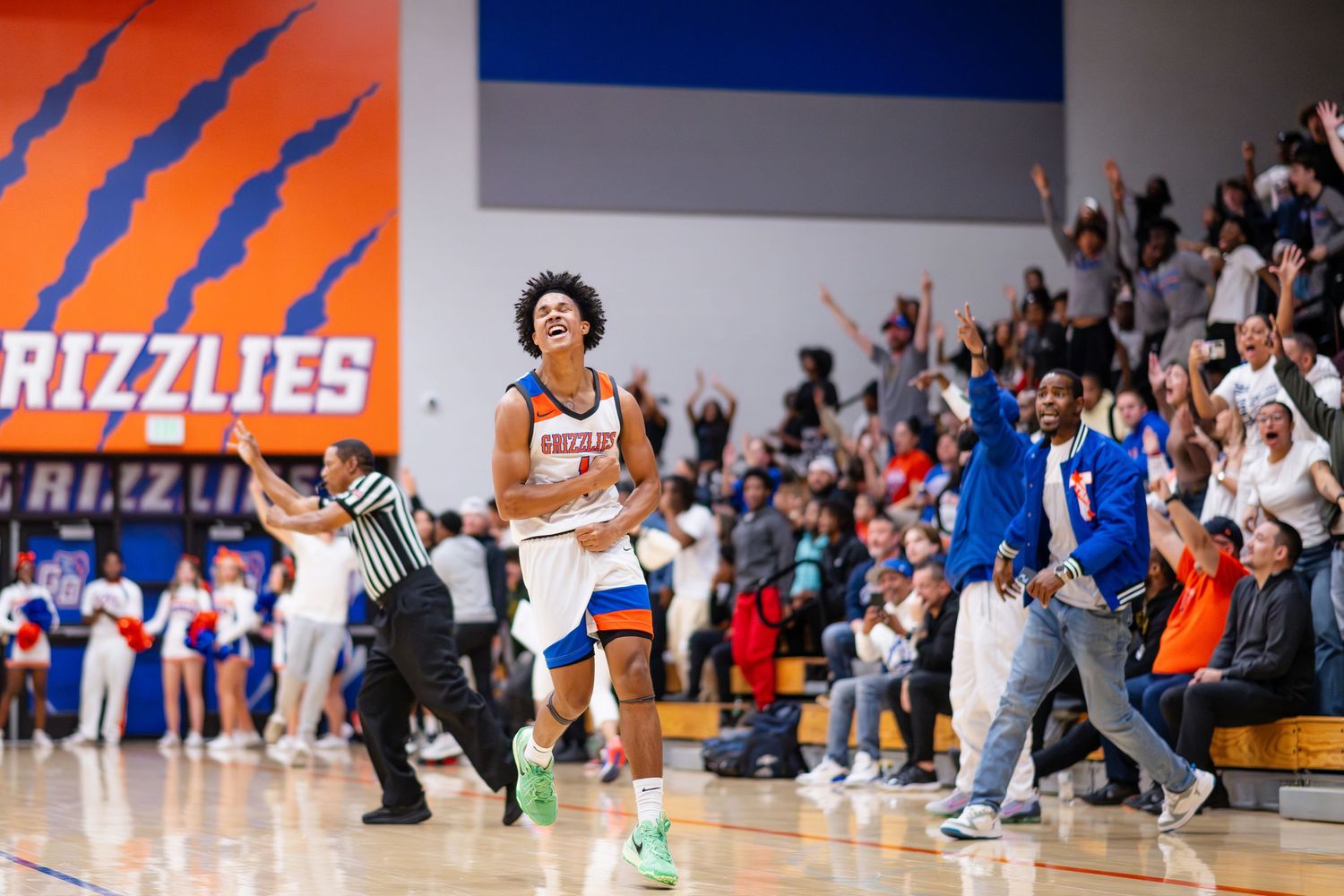 A basketball player celebrates triumphantly on the court as the crowd erupts behind him during a Grizzlies game.