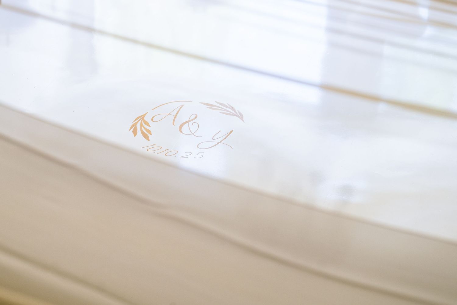 Close-up of elegant acrylic wedding stationery with gold monogram initials and delicate floral wreath design.