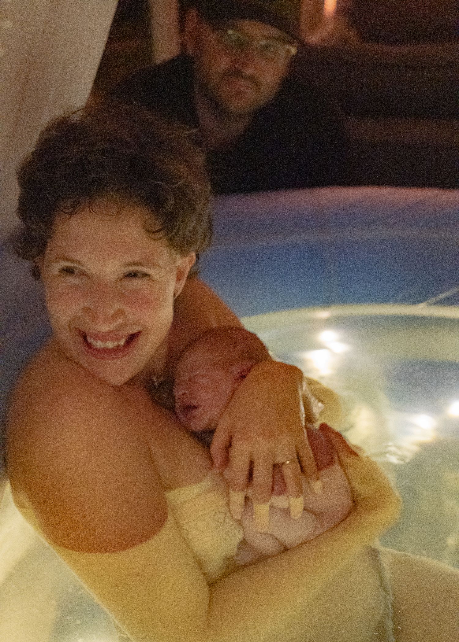 Mère tenant son nouveau-né dans l’eau lors d’un moment de naissance en Estrie