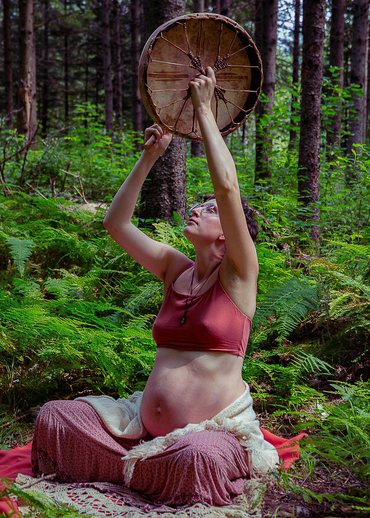 Femme enceinte en forêt avec un tambour lors d’une séance maternité en Estrie