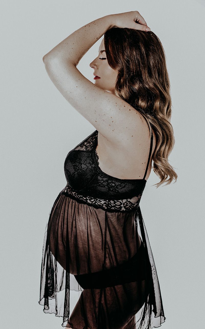 Silhouette einer schwangeren Frau im Fotostudio mit einem schwarzem Spitzenkleid.