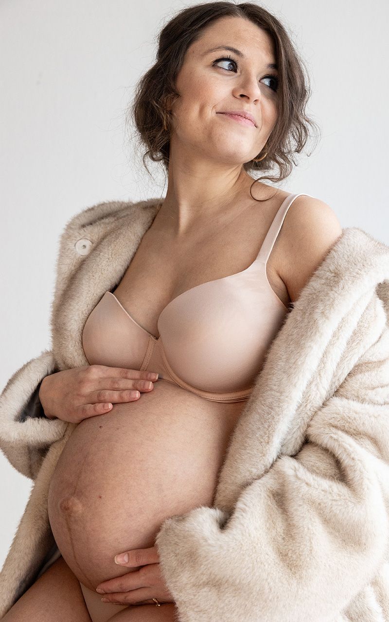Nahaufnahme einer schwangeren Frau im Studio, die ihr Bauch hält.