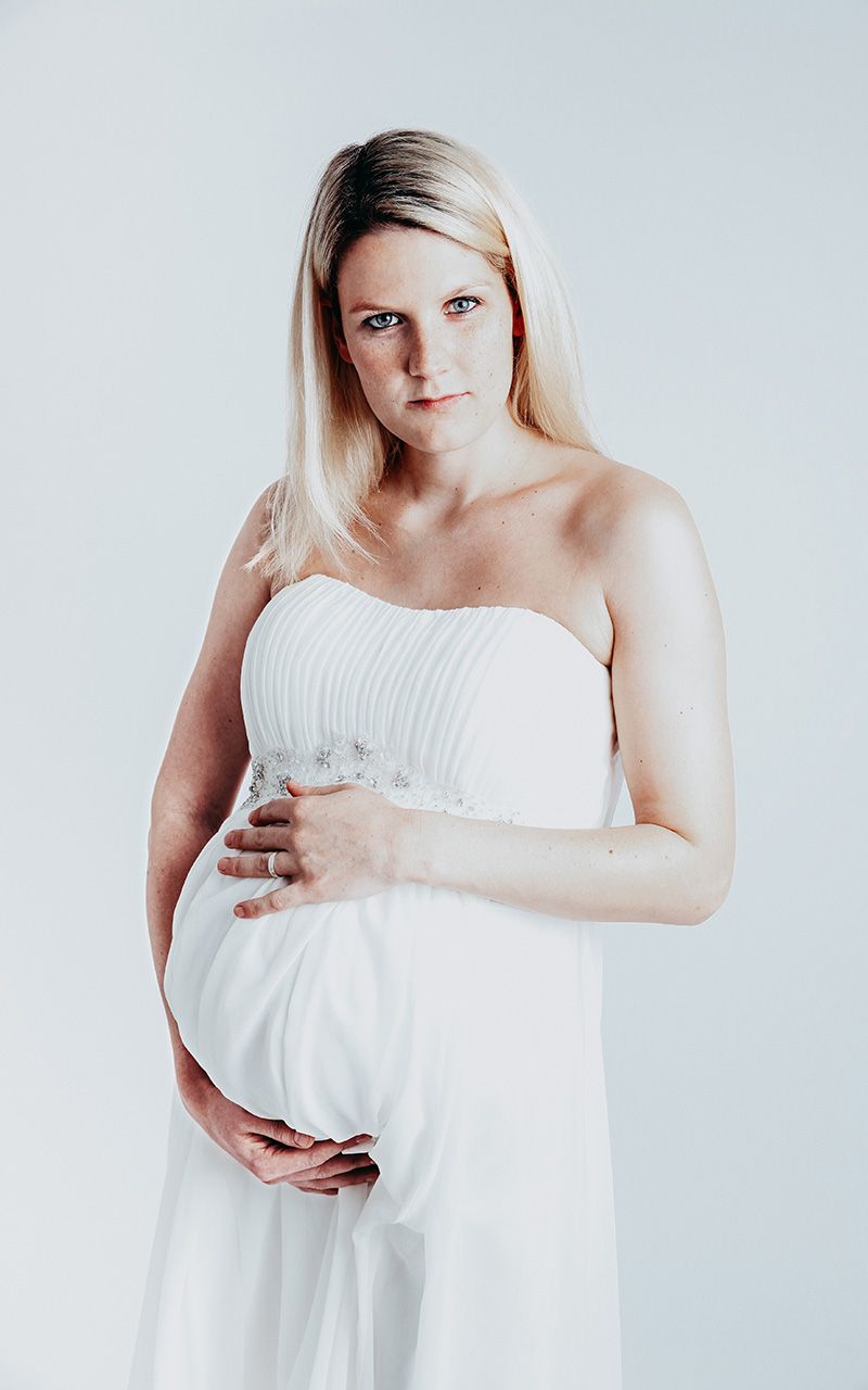 Schwangere Frau im Fotostudio mit weissem Hintergrund.
