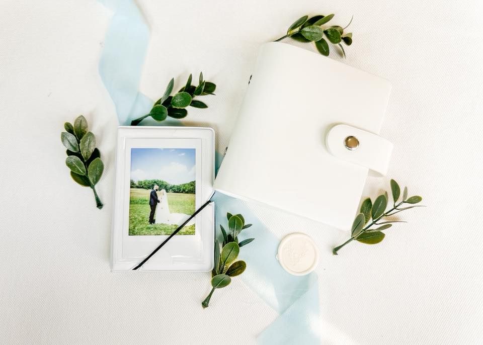 Elegant wedding photo album flatlay with greenery, ribbon, and a couple portrait print.