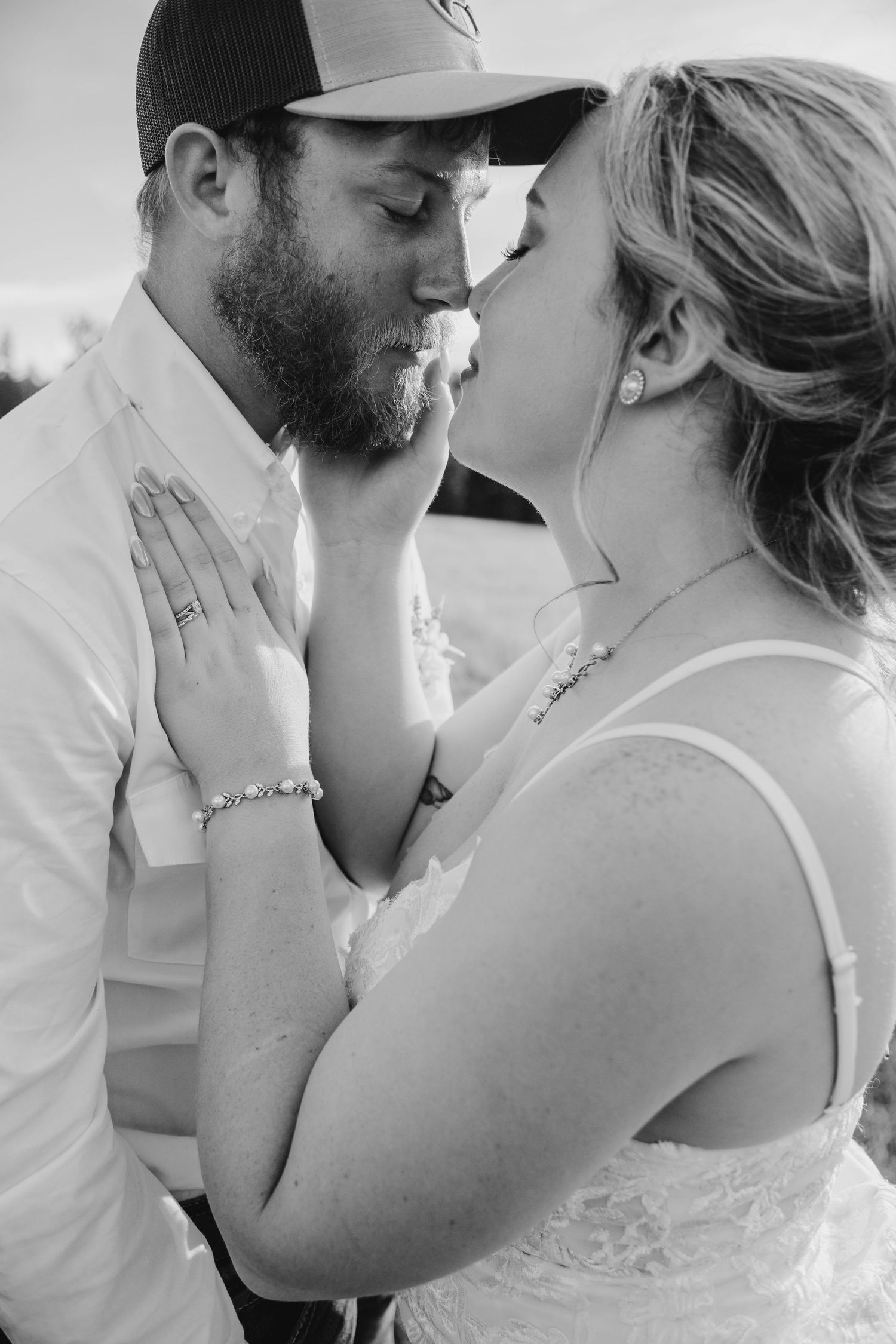 Black and white photo of a bride and groom sharing a kiss with wedding cake smeared on their faces.