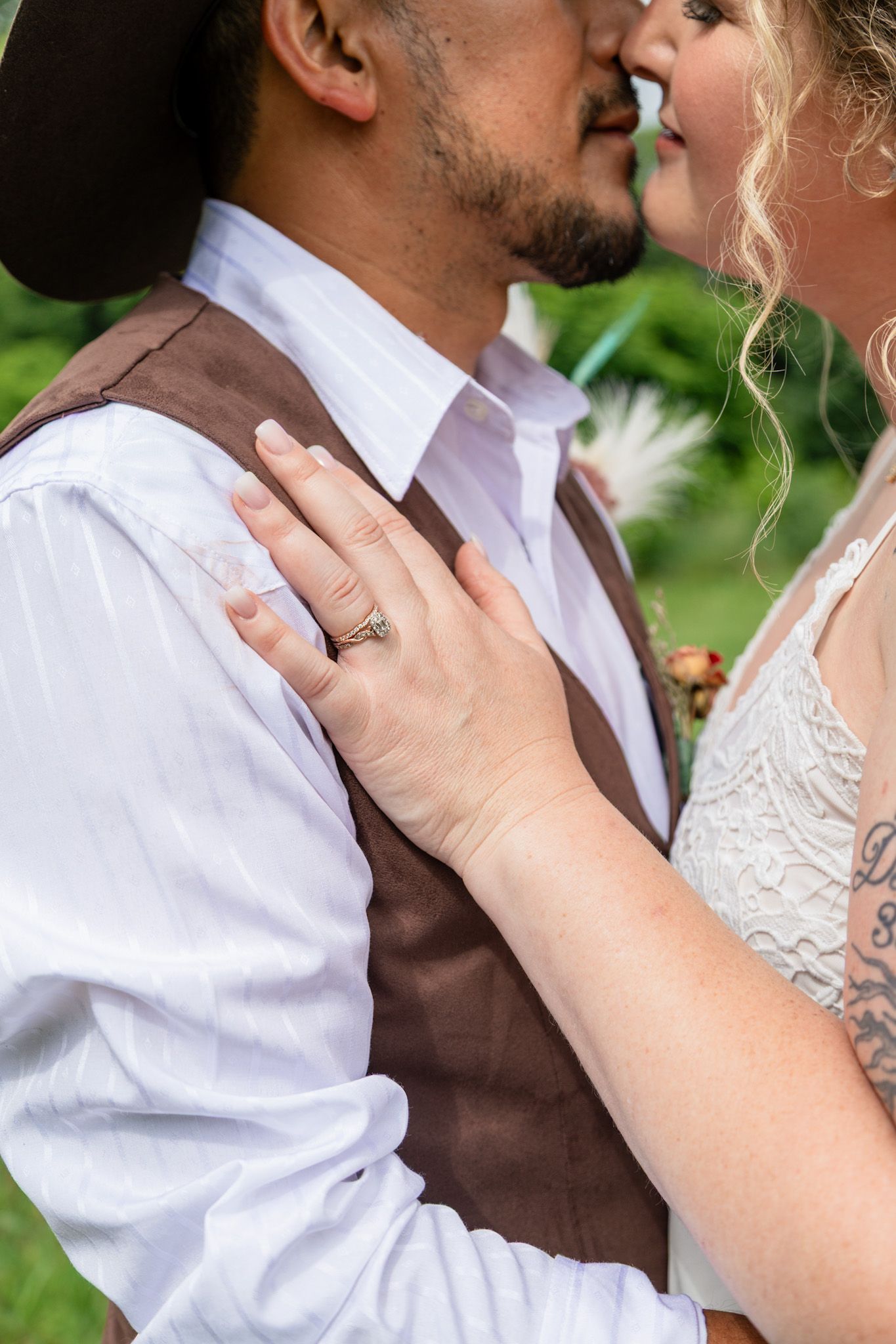 Close-up of bride and groom sharing a kiss with wedding ring visible on brides hand.
