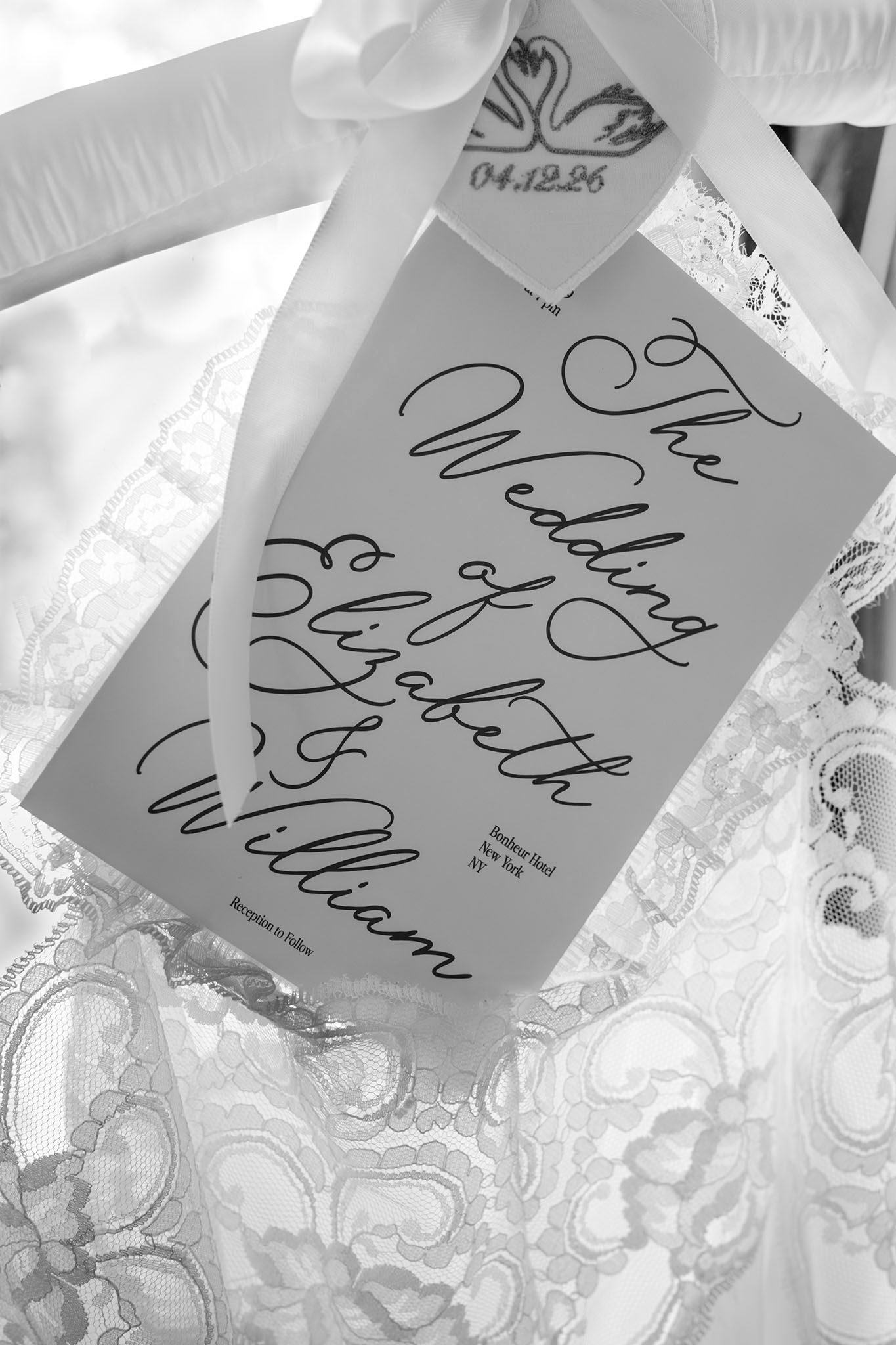 Black and white photo of a wedding program card for Elizabeth and William dated 04.12.26 on lace fabric.