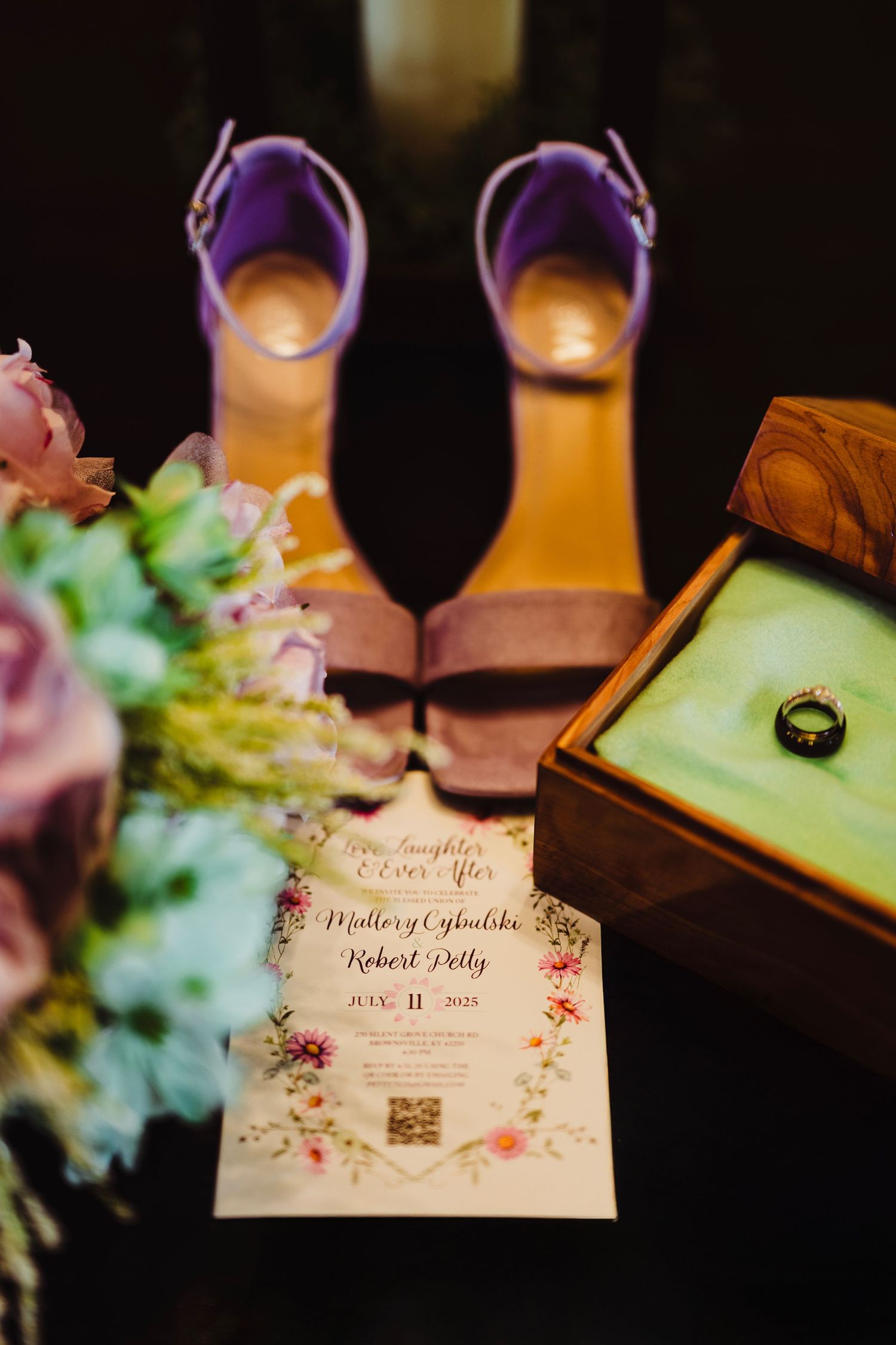 Wedding flat lay with purple heels, floral invitation, engagement ring, and bridal bouquet.