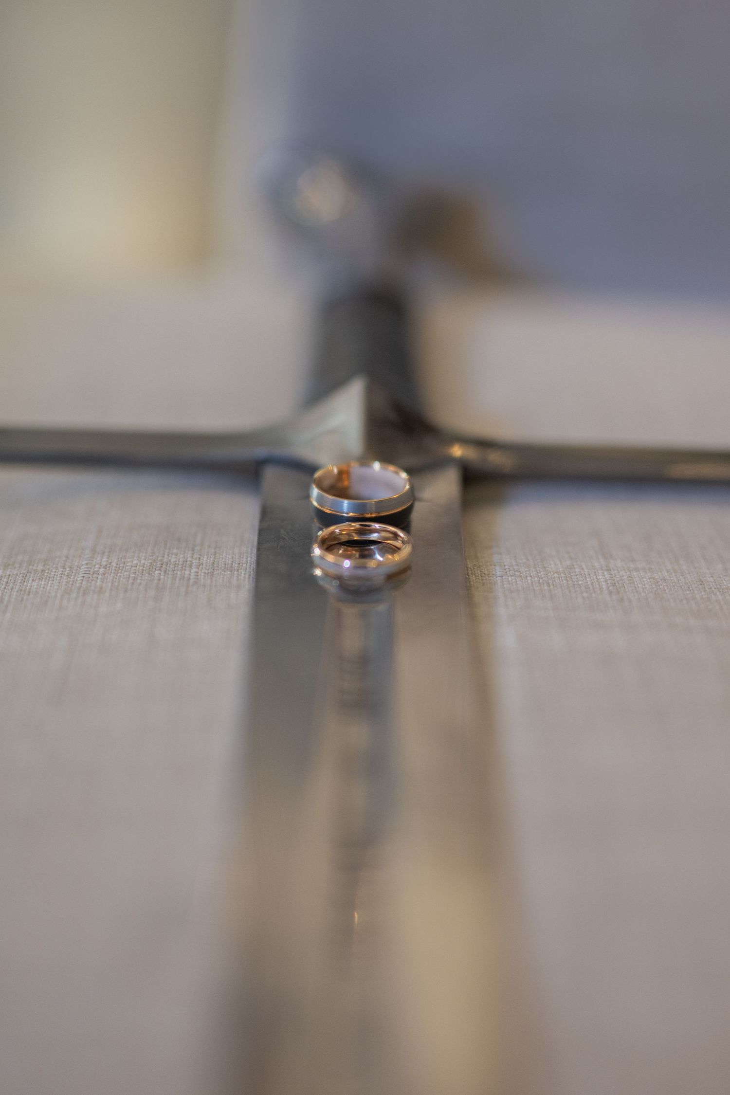 Two gold wedding rings resting on a silver cross, symbolizing marriage and faith.