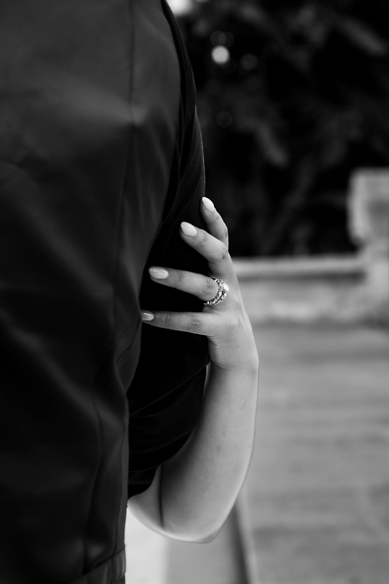 Black and white photo of a woman's hand with a ring resting on her hip in an elegant pose.