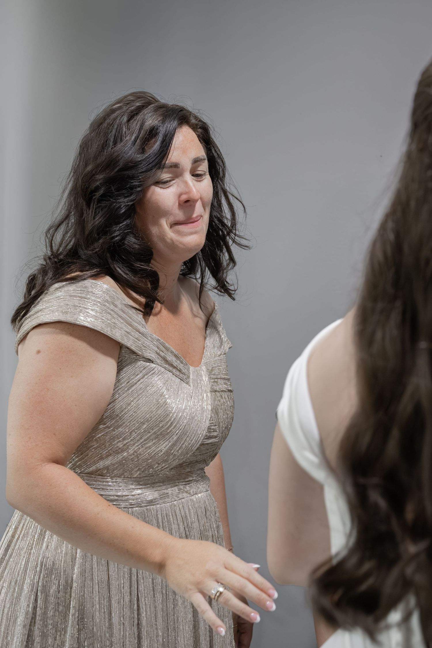 Emotional woman in gold dress crying with eyes closed at a wedding ceremony.